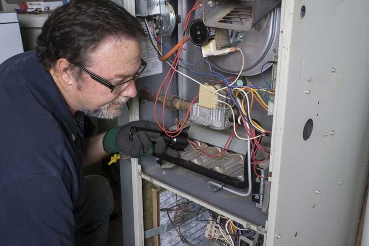 Technician-Looking-Over-A-Gas-Furnace-Fotolia_92684369_S HVAC Technician inspecting a furnace